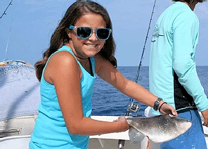 Happy young girl holding triggerfish during a wreck fishing charter.