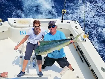 Lady angler and mate holding up a very large mahi